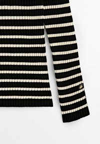 Zwart en crèmewit gestreepte rib gebreide trui met lange mouwen en een ronde halslijn. Voorzien van een gouden accentknop op de manchet van de mouw.