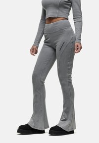 Grijze geribde uitlopende broek met een hoge tailleband, voorzien van zijnaht en zwarte accenten. Draag met zwarte plateauschoenen.