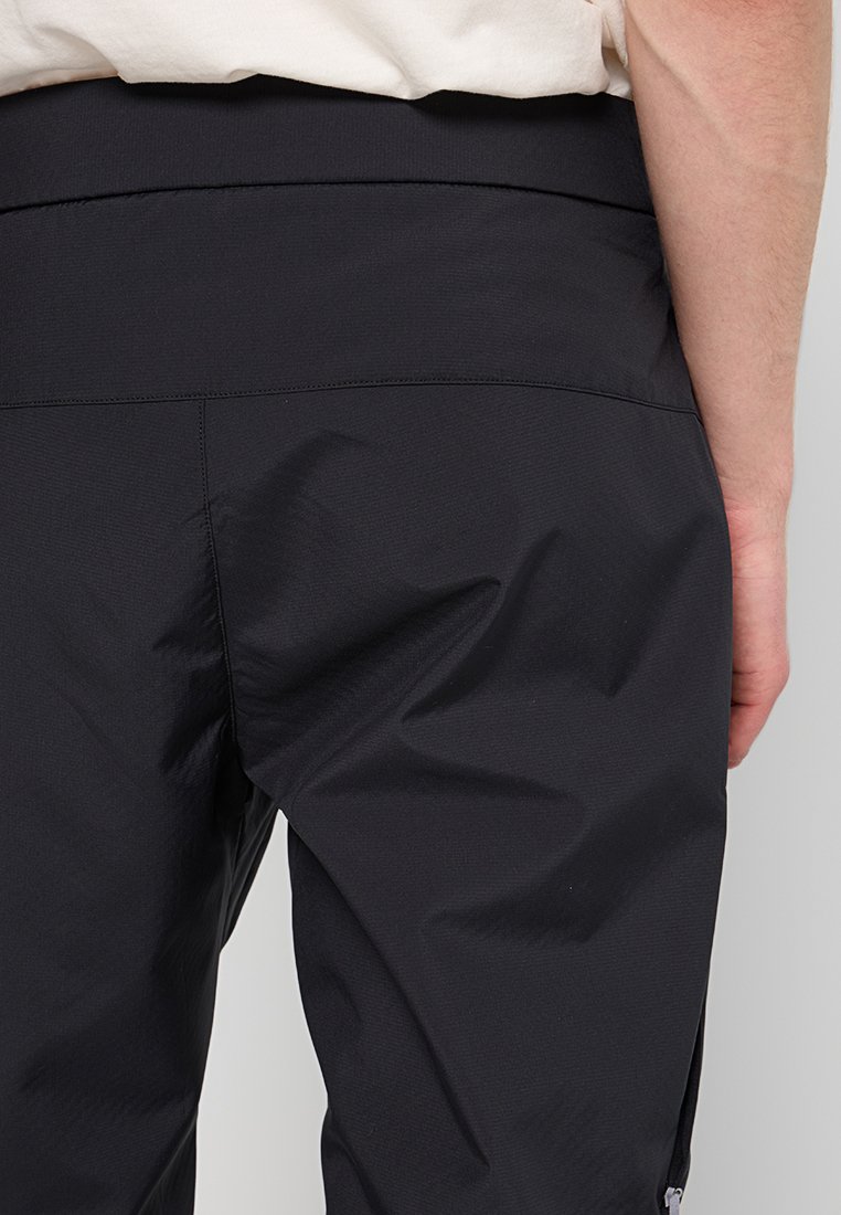 Schwarze Sporthose mit glatter Textur, ausgestattet mit einem breiten Bund und seitlichen Reißverschlusstaschen für zusätzliche Funktionalität.