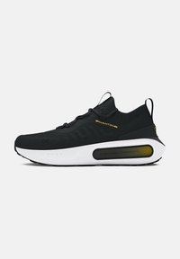 Chaussure de sport noire avec une tige texturée, des accents jaunes, une semelle intermédiaire blanche et un élément de coussin HOVR distinctif sur le côté.