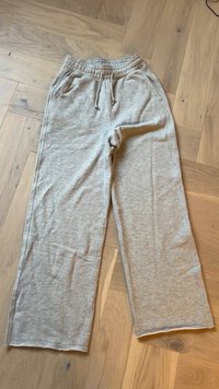 Grå sweatpants gjorda av mjukt tyg, med elastisk midja och dragsko, sidofickor och en avslappnad passform.