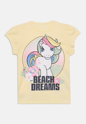Keltainen lasten t-paita, jossa on pastellinsävyinen yksisarvinen, trooppisia kukkia ja etuosassa teksti "BEACH DREAMS".
