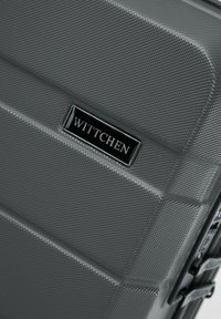 Šedý tvrdý kufr s texturovaným povrchem, výrazným černým logem WITTCHEN a dvojitými zipy pro bezpečné uzavření.