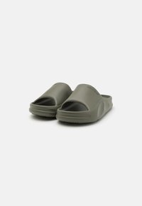Sandales en caoutchouc vertes avec un design à bout ouvert, finition mate lisse et semelle intérieure texturée pour une meilleure adhérence. Bords arrondis et semelle basse.