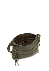 Zelena tkanina torba s zatvaračem na munju, koja ima više odjeljaka, podesivu trakicu i istaknute detalje šivanja.