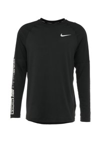Musta pitkähihainen paita, joka on valmistettu hengittävästä kankaasta. Paidassa on pieni valkoinen Nike-logo rinnassa ja rohkea "Just Do It" -teksti hihassa.