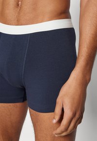 Marineblaue Boxershorts mit einem weißen elastischen Bund. Weicher Baumwollstoff, körperbetontes Design und flache Nähte für mehr Komfort.
