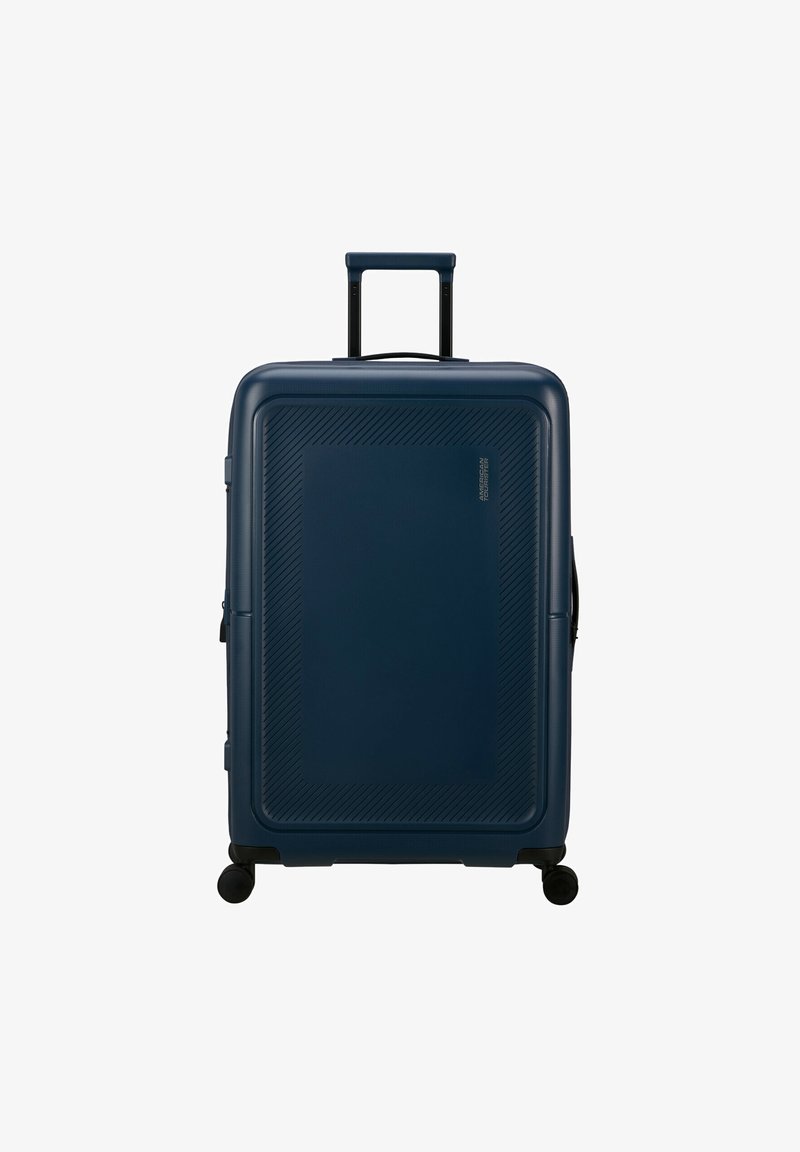 Valigia rigida di colore blu scuro, con motivi testurizzati diagonali, manico retrattile e quattro ruote girevoli per la mobilità.