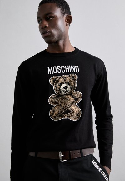 Fekete, hosszú ujjú póló, nyomtatott plüssmackó mintával és "Moschino" felirattal a tetején. Az anyag simának és könnyűnek tűnik.