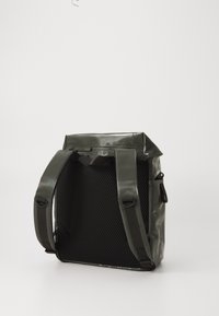 Sac à dos étanche vert avec une finition brillante, des panneaux en maille, des bretelles doubles et une fermeture enroulable pour un accès et un stockage sécurisés.