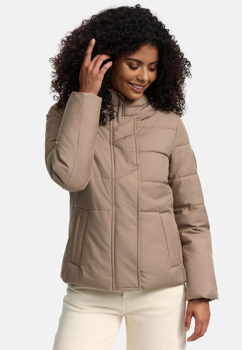 Veste matelassée beige avec un col montant, fermeture éclair et deux poches latérales. Caractérisée par un tissu texturé et un branding discret.