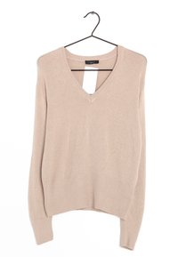 Pull en V couleur beige à manches longues avec ourlet et poignets côtelés, suspendu sur un cintre noir contre un fond blanc.