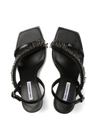 Melnas sandales ar kvadrātveida purngalu, sintētiskām siksnām un pērlītēm rotātu maliņu. Ievietots potītes sprādze un plakana zole ērtai valkāšanai.