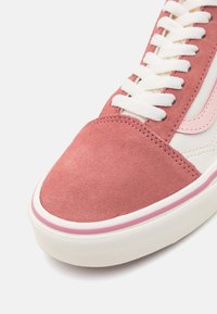 Rosa mockaskinnssneakers med vita snören, rund tå och kontrasterande rosa rand på sidan. Vit gummisula med strukturerad yta.
