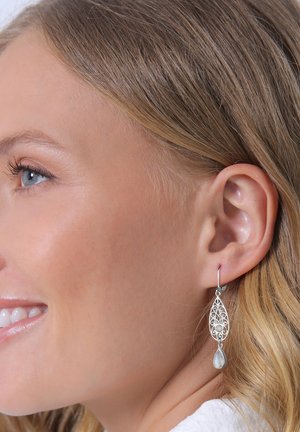 Boucles d'oreilles en filigrane argenté avec un accent en forme de goutte de pierre de lune. Design complexe semblable à de la dentelle, léger et élégant.