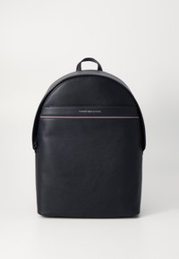 Mochila de cuero negro con un extremo redondeado, que presenta una franja frontal con el logotipo, un cierre de cremallera y un asa en la parte superior.