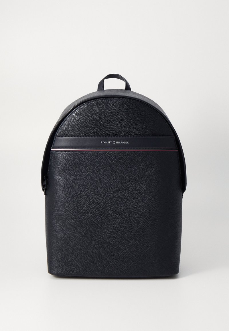 Mochila de cuero negro con un extremo redondeado, que presenta una franja frontal con el logotipo, un cierre de cremallera y un asa en la parte superior.