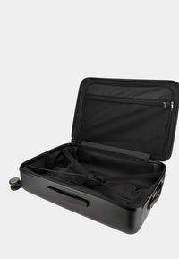 Valise rigide noire avec un design ouvert. Comprend des sangles internes, une poche en maille et des roues lisses pour la mobilité. Surface texturée.