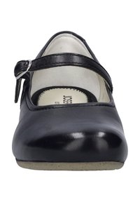 Chaussure Mary Jane en cuir noir avec un bout rond, une bride sur le coup de pied et une semelle plate. L'intérieur présente un branding minimal.