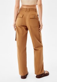 Bruna cargobyxor med avslappnad passform, två bakfickor, sidofickor samt stickade detaljer. Tillverkade av slitstarkt bomullstyg.