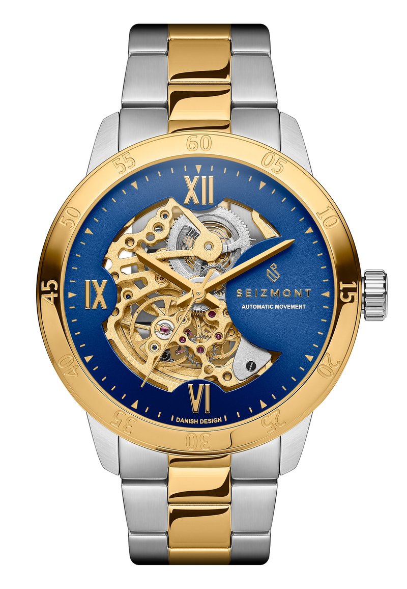 Gul och silver rostfritt stål automatisk klocka med en blå skelettkrona, guldaccenter, numrerade timmarkörer och synliga rörelsemekanismer.