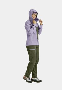 Light lavender jacket with a hood, zippered front, and gray accents paired with dark green pants featuring cargo pockets and multi-colored footwear.