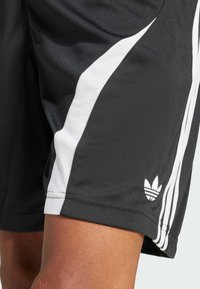 Shorts de sport noirs avec des panneaux latéraux en maille blanche et trois bandes verticales blanches. Présente un petit logo blanc à l'ourlet.