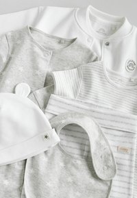 Grau-weiße Babybekleidungsstücke, darunter ein Body mit Sternmuster, ein gestreiftes Shirt, ein Lätzchen und eine Mütze mit Sternakzent. Weicher Stoff.