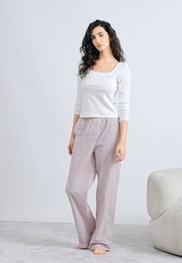 Bijela majica s dugim rukavima i kvadratnim izrezom na vratu. Hlače u svijetlo sivoj i bordo boji s prugama i elastičnim pojasom. Jednostavan dizajn, mekani materijal.