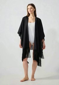 Musta kimono-tyylinen peittokappale, joka on valmistettu kevyestä kankaasta. Siinä on avonaiset hihat, fringettu helmustus ja herkät pitsiyksityiskohdat kaula-aukossa.