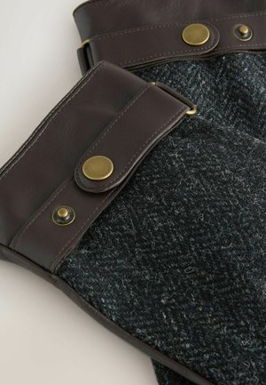 Villa-sekoite säärenlämmittimet, joissa tummaharmaa tekstuuri; ruskeat nahkakoristeet ja messinkiset napit yläosassa säädettävää istuvuutta ja tyyliä varten.