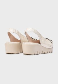 Zapatos de plataforma blancos tipo slingback con un patrón de cocodrilo texturizado, que cuentan con un interior marrón y una suela gruesa y estriada.