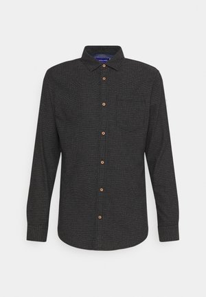 Chemise noire à manches longues boutonnée, avec une texture subtilement pointillée et des boutons marron, dotée d’un col plié et d’une poche poitrine unique.