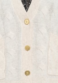 Cardigan lavorato a maglia off-white con motivo a treccia, sei bottoni dorati, scollatura a V e bordi a costine. Due tasche frontali con texture sottile.