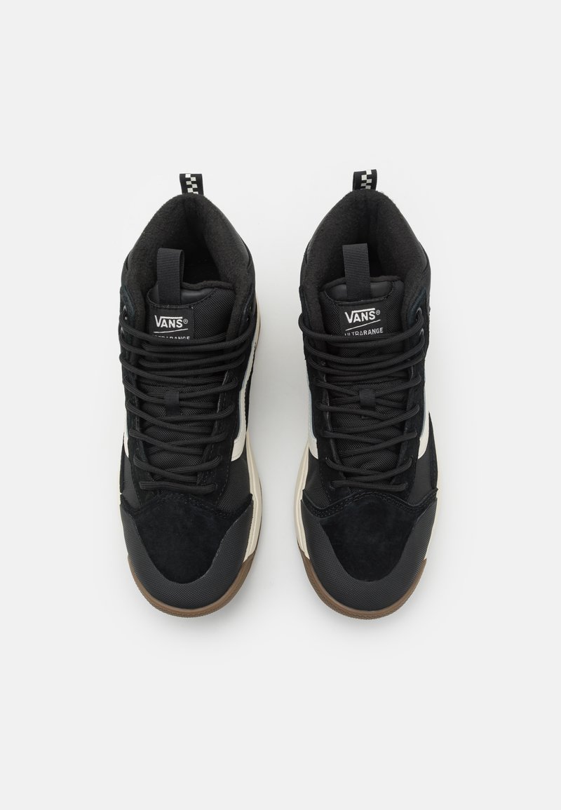 Magas szárú fekete sportcipők velúr és hálós panelekből, fekete fűzőkkel, fehér csíkkal és barna gumitalppal. A VANS logó a nyelvén található.