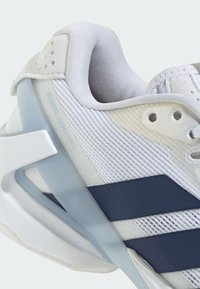 Gros plan d'une chaussure de course blanche et bleu marine avec tissu en mesh, col de cheville rembourré et support de talon en plastique angulaire.