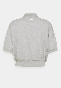Pull-over à manches courtes gris clair avec ourlet élastique et petit logo Nike sur le haut du dos.