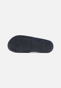 Black rubber sneaker sole with patterned texture, featuring rectangular and circular shapes, designed for traction and durability.