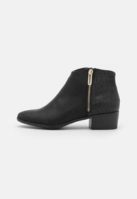 Schwarze Knöchelboots mit strukturiertem Absatz, seitlichem Reißverschluss und niedrigem, gestapeltem Absatz auf einem weißen Hintergrund, im linken Profil dargestellt.