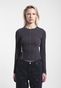 Top a maniche lunghe a coste di colore grigio scuro con cuciture a contrasto di un blu chiaro, caratterizzato da un design aderente e da un collo rotondo.