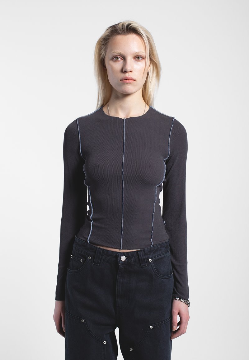 Top a maniche lunghe a coste di colore grigio scuro con cuciture a contrasto di un blu chiaro, caratterizzato da un design aderente e da un collo rotondo.
