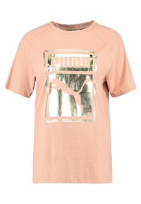 Růžové oversized tričko z bavlny s metalickým zlatým obdélníkovým logem Puma a siluetou skákajícího pumy ve středu.