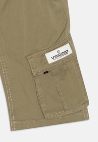 Shorts cargo en khaki présentant une grande poche latérale et une étiquette avec un texte noir. Fabriqués à partir d'un tissu durable avec des coutures visibles.