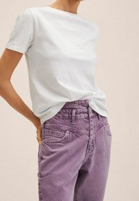 Camiseta de manga corta azul claro hecha de suave algodón, combinada con jeans morados desgastados de talle alto que cuentan con cinco bolsillos y pasadores para cinturón.