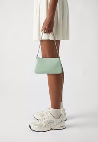Mint green leather clutch bag with a silver chain strap, rectangular shape, and a minimalistic design. Features a zip closure and logo detail.