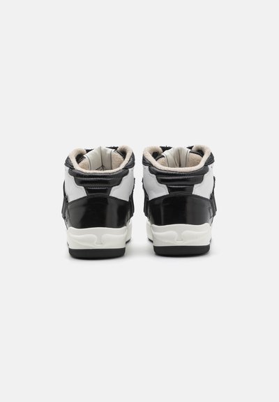 Black and white high-top sneakers with a glossy finish, padded collar, and contrasting laces. Features light-colored interior and textured sole.