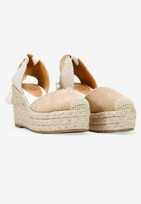 Cuñas de esparto beige con puntera de ante, suela de yute trenzado y correas de tela texturizada en el tobillo con un detalle de lazo.