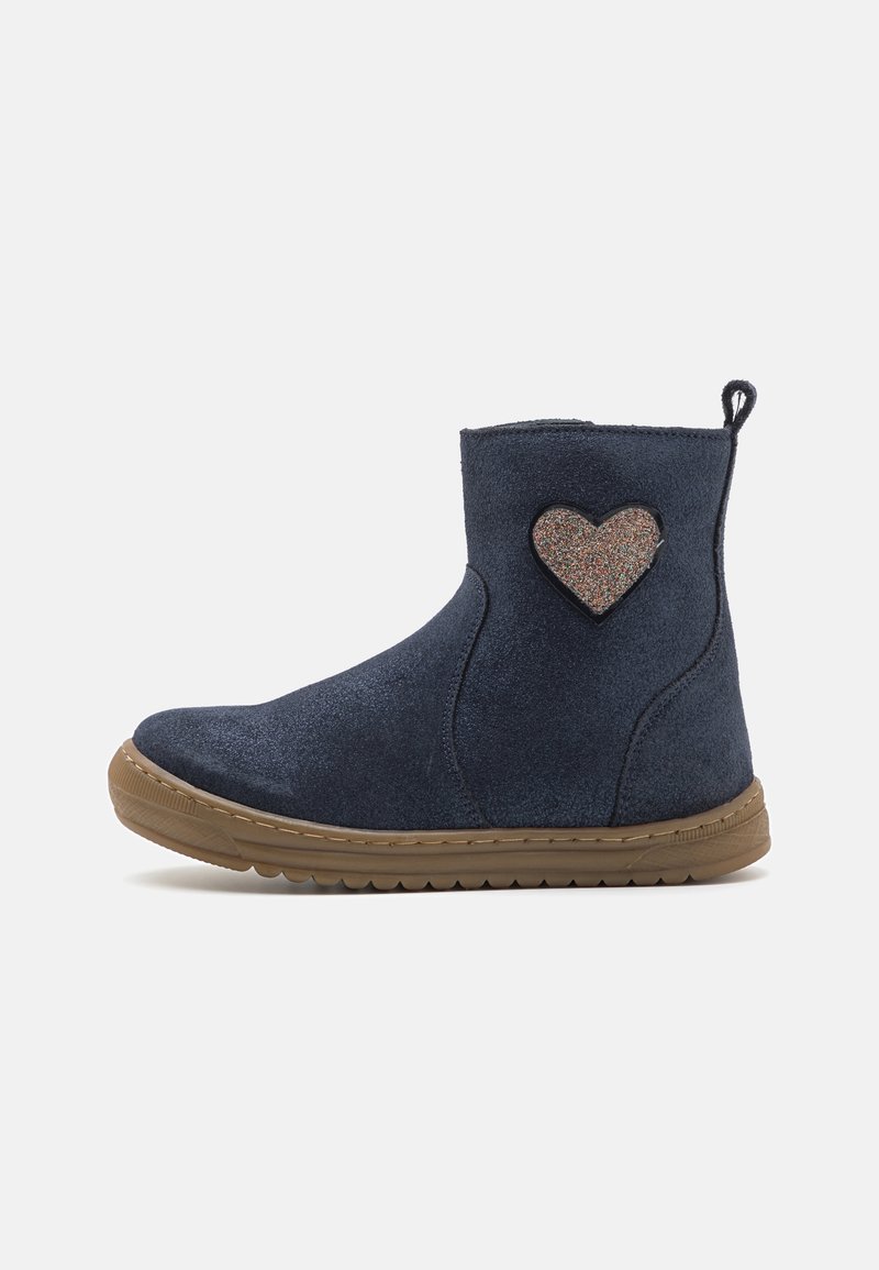 Bottine en daim bleu marine avec semelle en caoutchouc marron et patch cœur pailleté sur le côté extérieur, languette de traction à l'arrière.