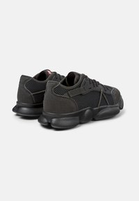 Black athletic shoes with a combination of mesh and soft fabric. Features a thick, textured rubber sole and reinforced heel for support.