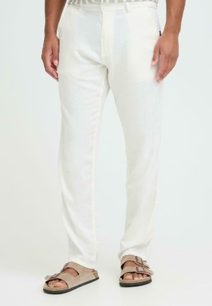 Hvide, lige ben bukser lavet af letvægtsstof med en glat tekstur og subtil glans, kombineret med brune, åbne tå-sandaler.